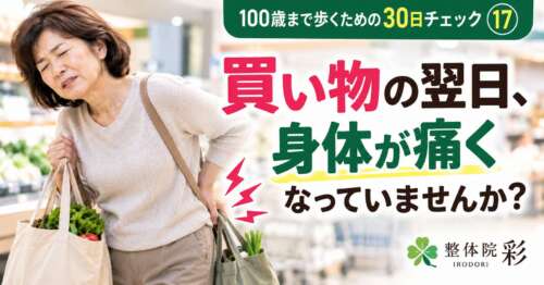 買い物袋を持った女性が腰に手を当てる様子。「100歳まで歩くための30日チェック⑰ 買い物の翌日、身体が痛くなっていませんか?」と問いかける整体院 彩の健康チェック画像。